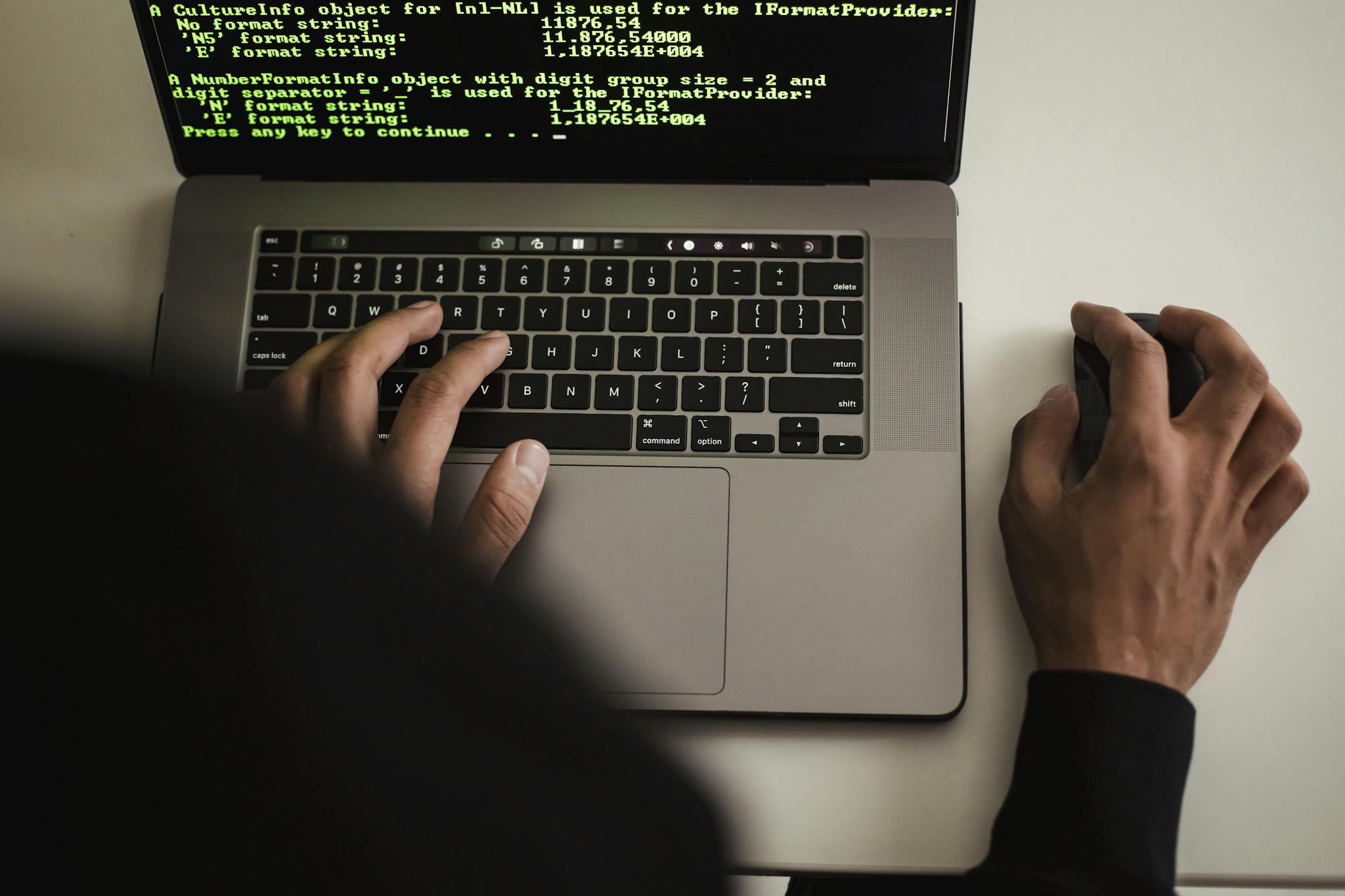 Close-up of a programmer typing on a laptop, displaying code on the screen.